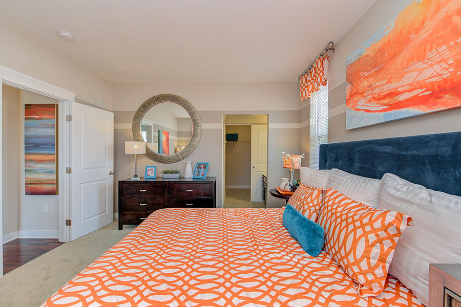 Bright color orange decorated bedroom with a circle mirror located at One One Six Apartments